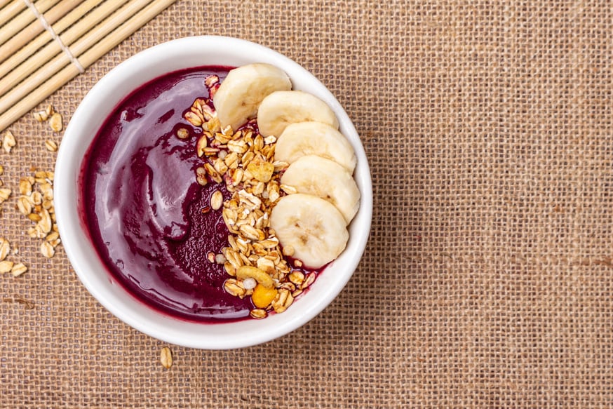 Acai bowl with banana and granola on textured jute canvas. Brazilian Acai.